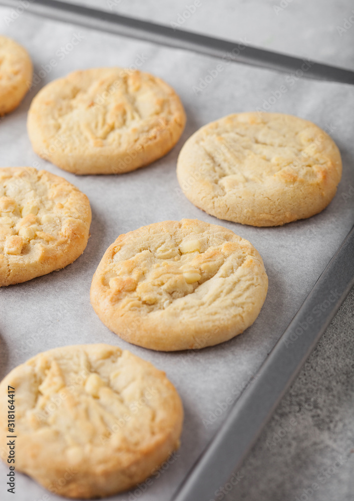 White chocolate biscuit cookies on baking tray on light kitchen table background.