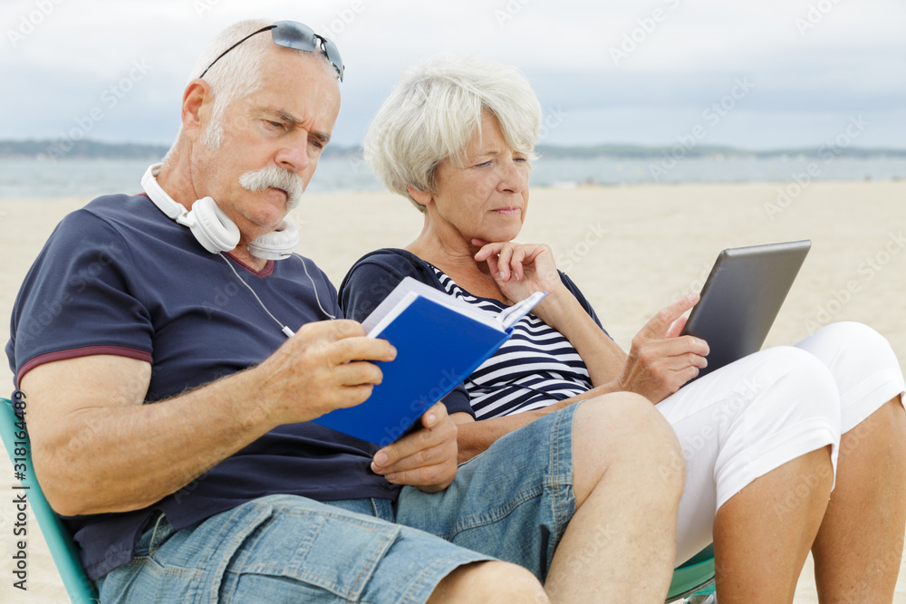 man and wife reading a book on the beach man and wife reading a book on the beach