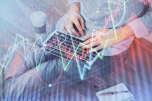 Forex graph with businessman working on computer in office on background. Concept of analysis. Double exposure.