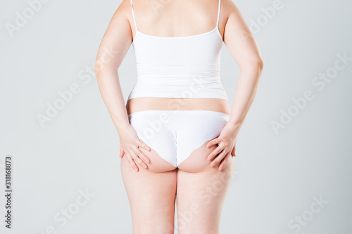 Overweight woman with fat legs and buttocks, obesity female body on gray background