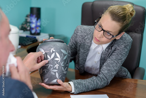 funeral director looking at urn with tearful client photo