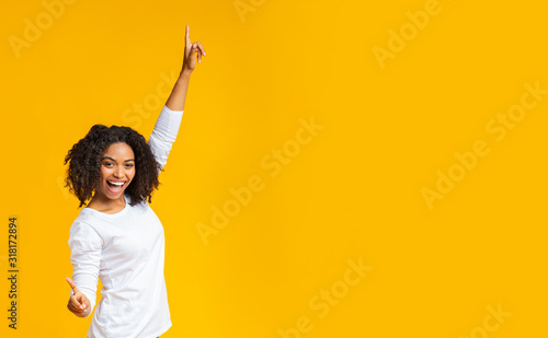 Joyful african american girl dancing, raising hands and looking at camera