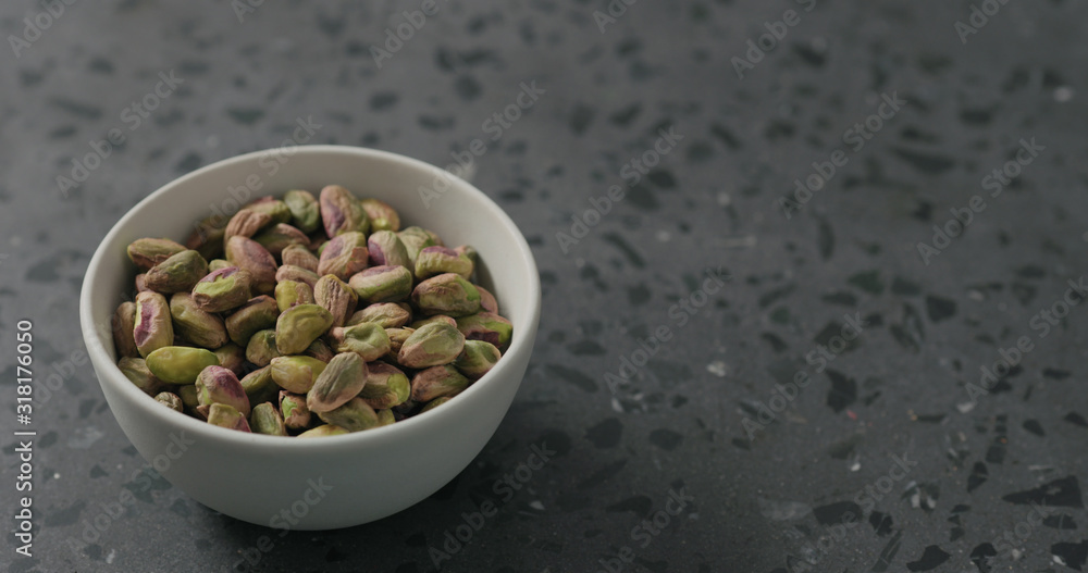 peeled pistachios in white bowl on terrazzo surface peeled pistachios in white bowl on terrazzo surface