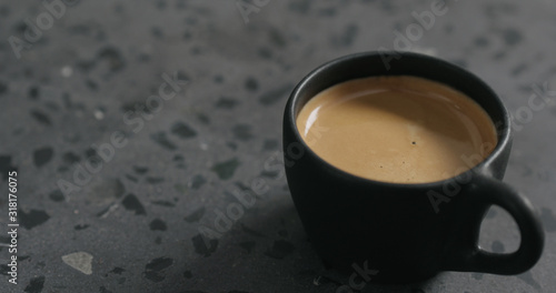 fresh espresso in black cup on terrazzo surface