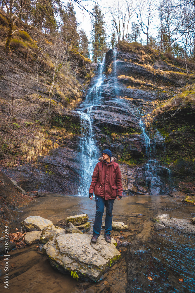A young man enjoying in a beautiful waterfall in winter
