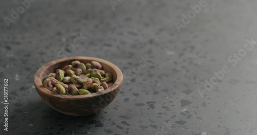 peeled pistachios in olive bowl on terrazzo surface