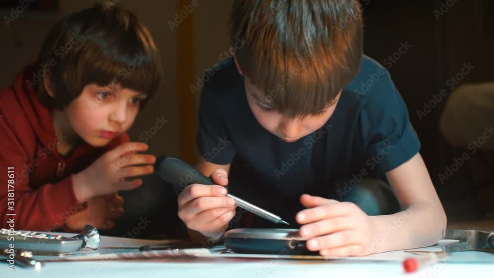 Two brothers are repairing an electrical appliance Two brothers are repairing an electrical appliance