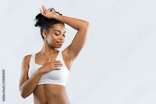 Happy black woman smelling her armpit over grey background