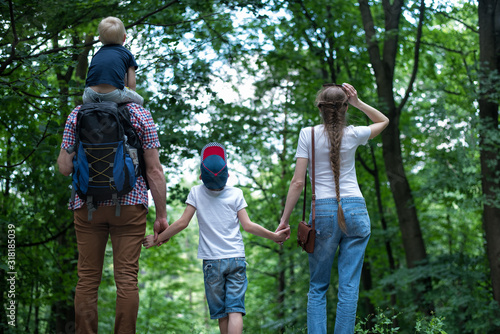 Family walks in nature. Mom, dad and two sons. Close-knit family. Back view © somemeans