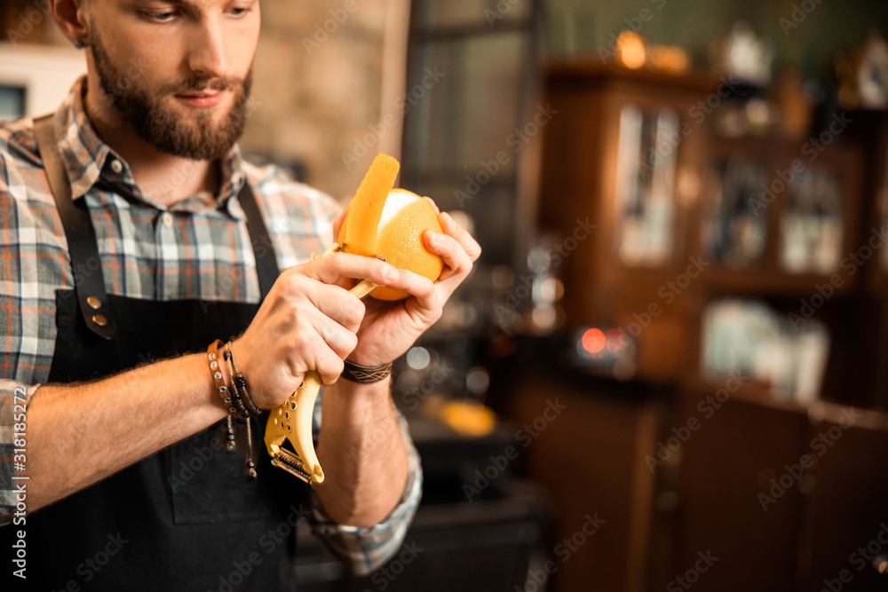 Fotografie Young bearded barman is making cocktail decorations