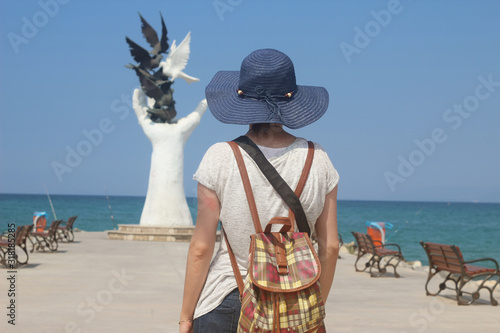 Kusadasi, Turkey the blue peace monument in front of the tourist with the hat and the bag