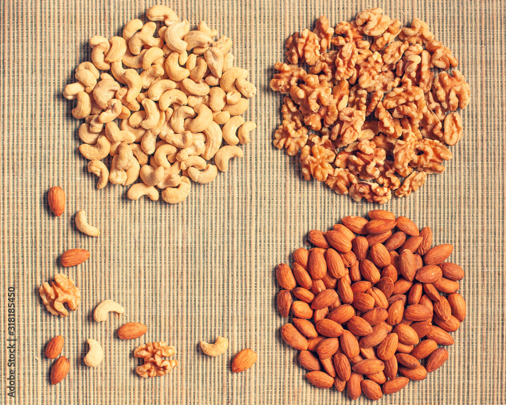 Background of different nuts (cashew, almonds, walnuts)  in shapes of a circle on a straw mat with a place for a text