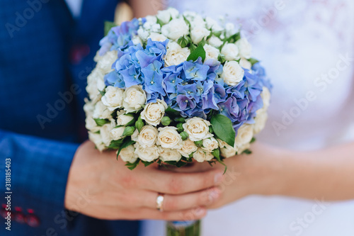 The bride and groom are holding in their hands with rings a wedding portrait of roses and chrysanthemums close-up. Wedding portrait of flowers. Photography, concept.