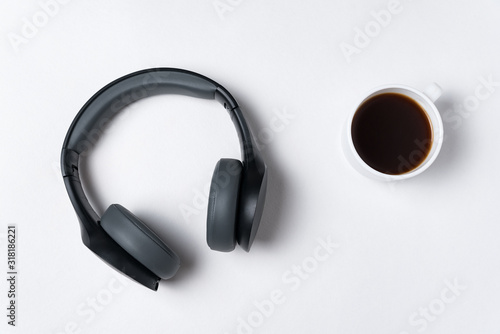 Headphones and cup of coffee on white background, top view. Minimalism.