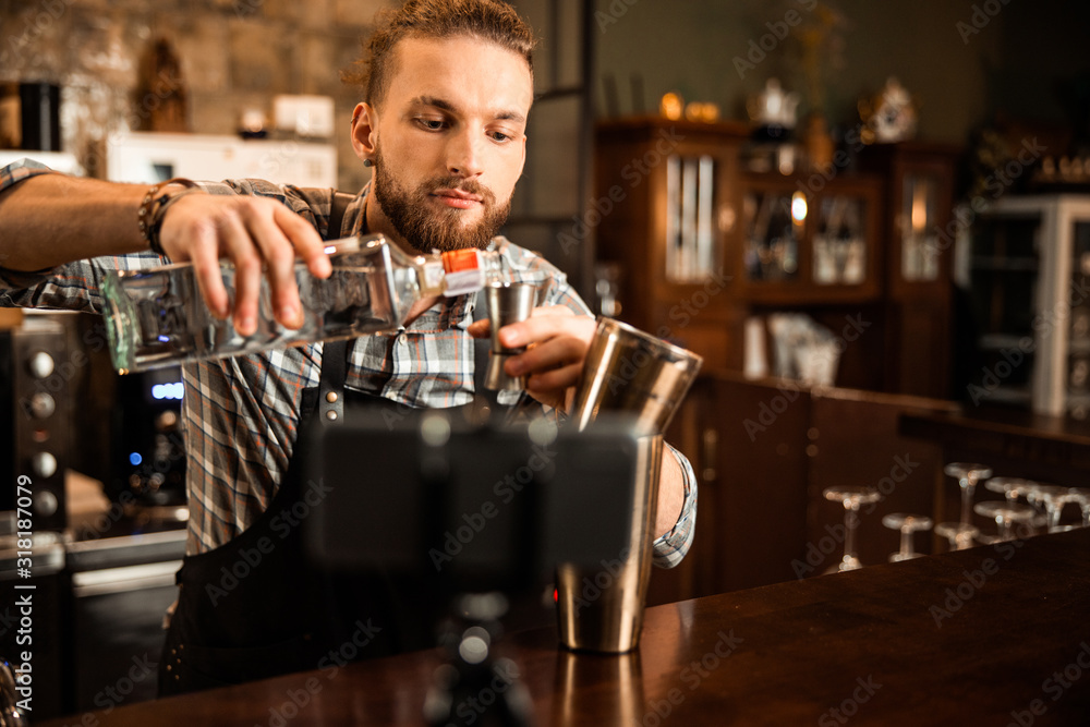 Young bartender filming vlog about his work
