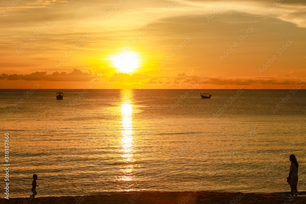 Silhouette of mother and son in sunset beach at Khao Lak, Phang Nag, Thailand.