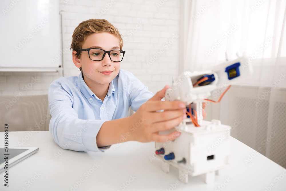 Clever schoolboy constructing robot at stem educational class Clever schoolboy constructing robot at stem educational class