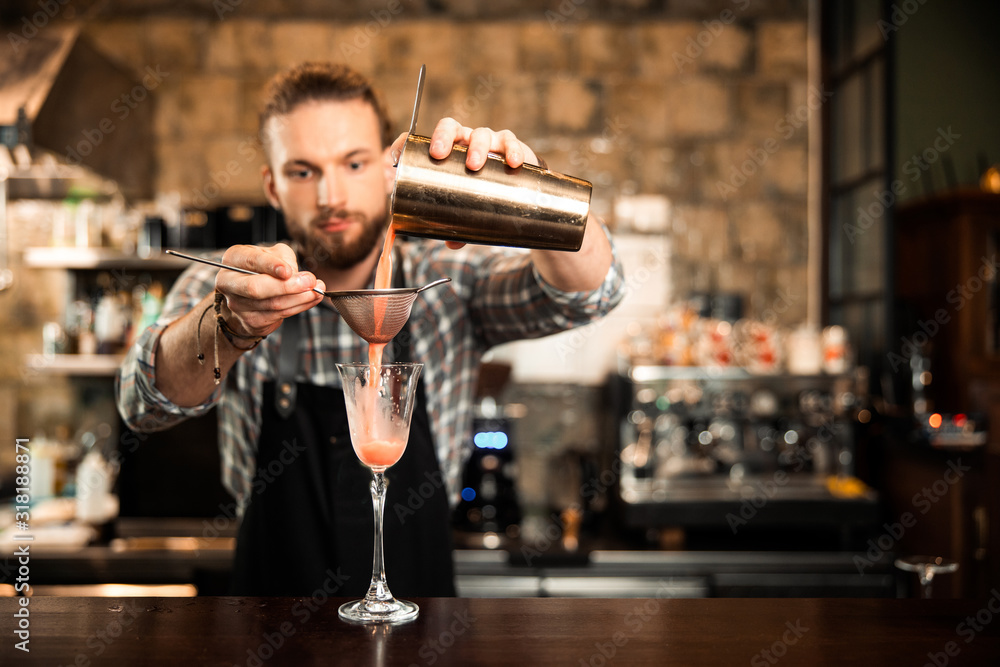 Male bearded bartender is making fancy cocktail