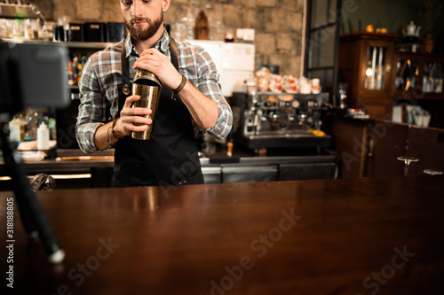 Bearded barman is making alcoholic cocktail behind the bar