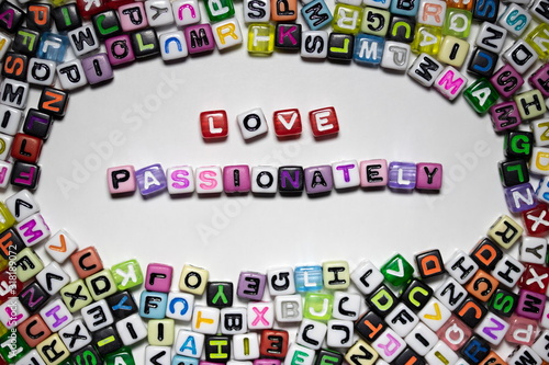The noun and adjective LOVE PASSIONATELY written with colorful cubes isolated on a white background...