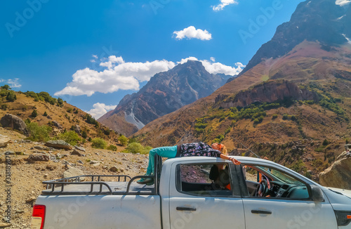 Beautiful young lies on the roof of a pickup truck on the background of the beautiful mountains of Tajikistan
