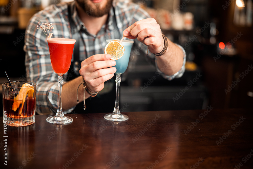 Barman decorating cocktail with a slice of orange