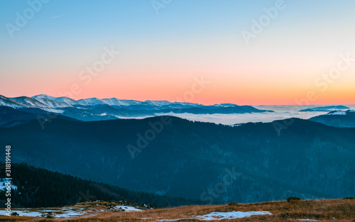 Mountain range with visible silhouettes through the morning colorful fog.Tarcu Mountains in Romania. photo