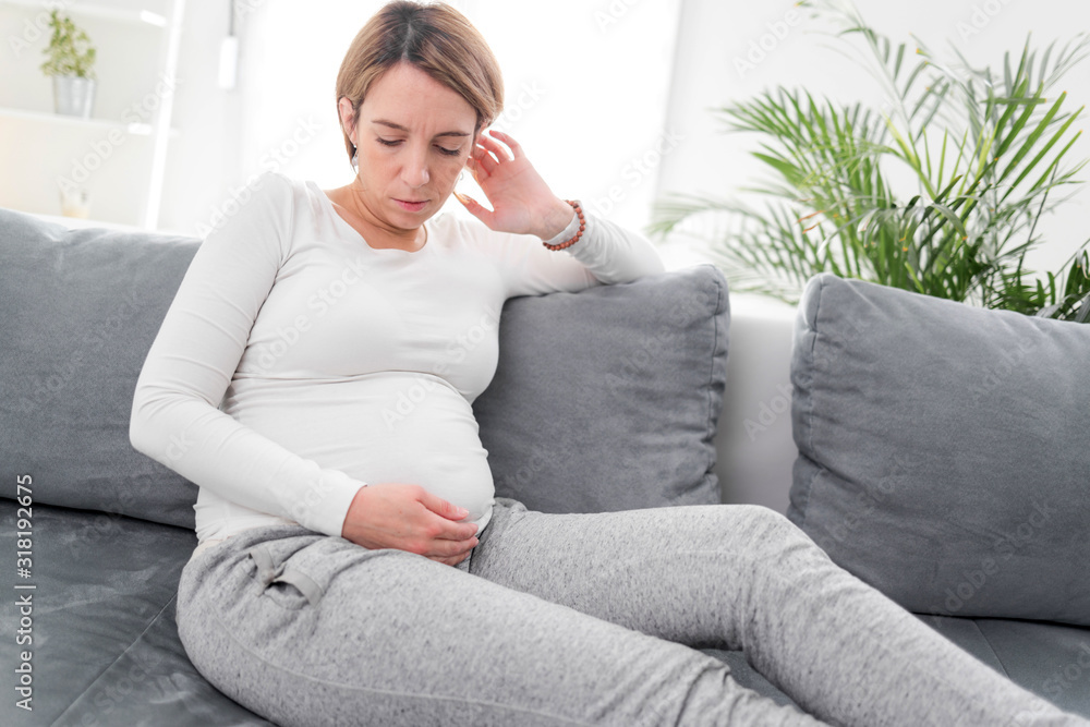 Pregnant tired exhausted woman with stomach and pain issues at home on a couch, being sick. Pregnant tired exhausted woman with stomach and pain issues at home on a couch, being sick.