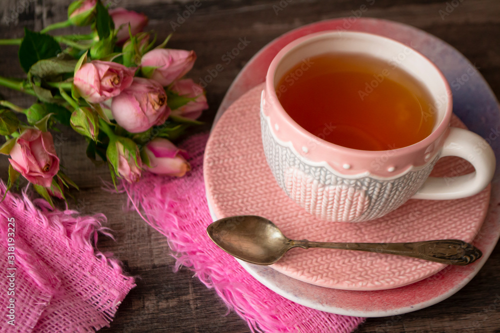 pink knitted cup of tea with heart on dark background decorated with pink roses