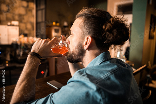 Bearded man sitting at bar counter and drinking