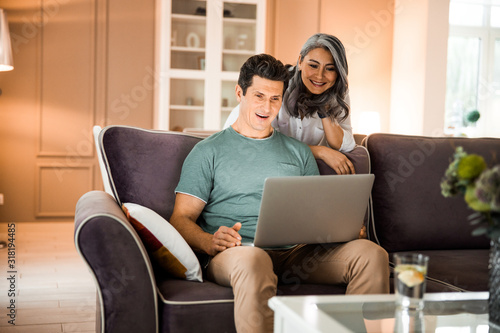 Happy mature man using laptop in living room