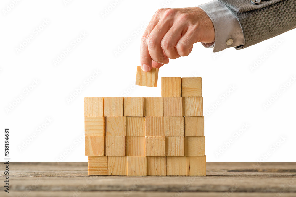 assembly concept of geometric shapes a man's hand on a wooden table. assembly concept of geometric shapes a man's hand on a wooden table.
