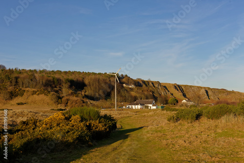 The Wind Turbine, Information Centre and other White Painted Buildings of the St Cyrus National Nature Reserve, seen from one of the many Footpaths.