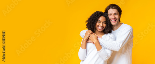 Joyful interracial sweethearts embracing and posing to camera
