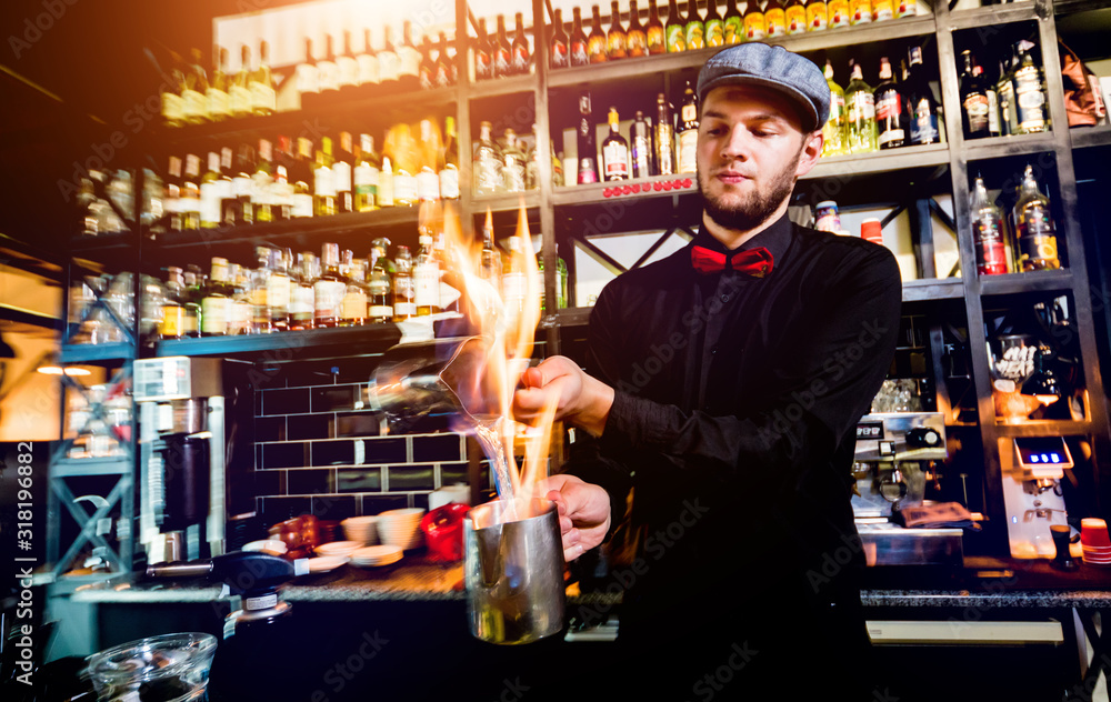The bartender makes a cocktail with a fire show at the bar. Bartender at work.