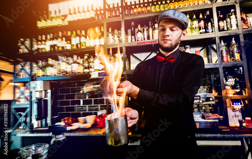 The bartender makes a cocktail with a fire show at the bar. Bartender at work.