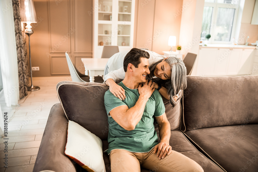 Fototapeta premium Smiling pretty woman hugging her husband at home