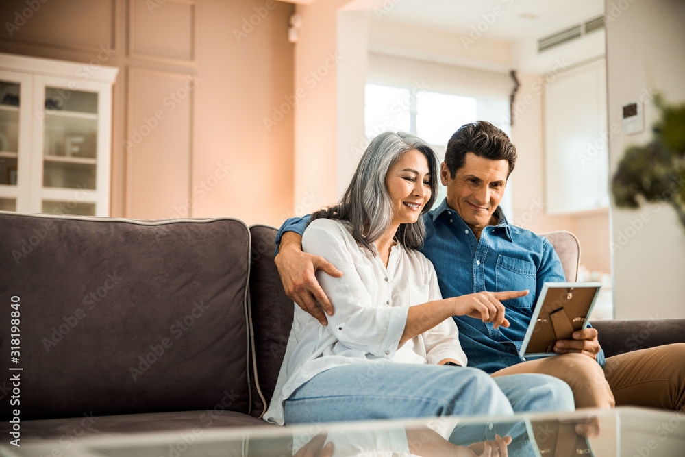 Happy adult couple in love looking at photo frame in room