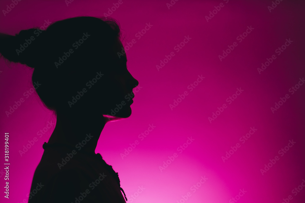 dark silhouette of a woman profile isolated on a pink background with copy space dark silhouette of a woman profile isolated on a pink background with copy space