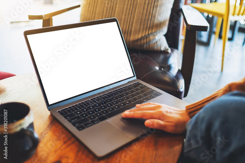 Mockup image of a woman using and touching on laptop touchpad with blank white desktop screen on the table
