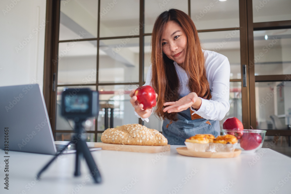 A beautiful asian woman food blogger or vlogger recording a video on camera