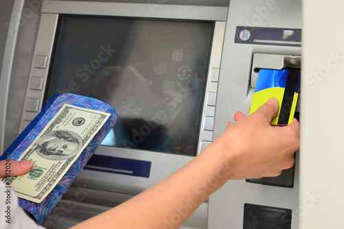 A woman inserts a plastic card into an ATM to withdraw cash.