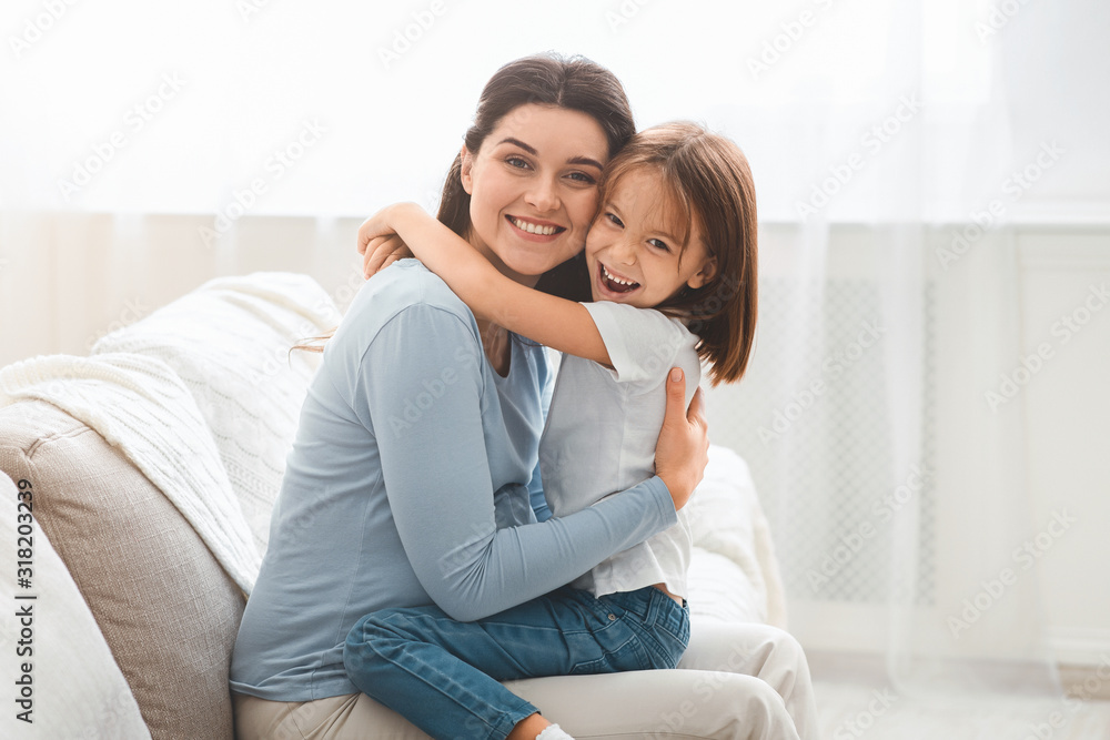 Little daughter and young mother hugging each other at home Little daughter and young mother hugging each other at home