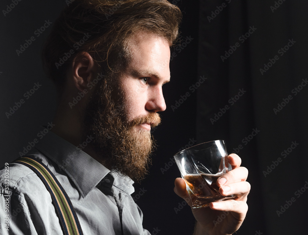 Portrait of a pensive handsome young man, with a glass of alcohol in his hands. Portrait of a pensive handsome young man, with a glass of alcohol in his hands.
