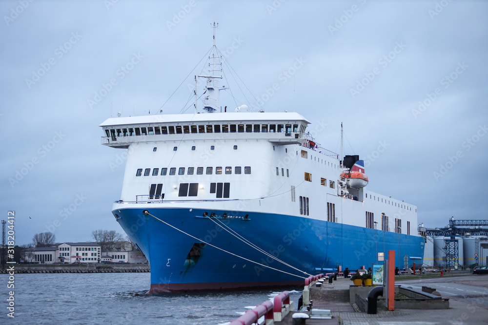 Big blue cargo ship docked at small baltic sea port.