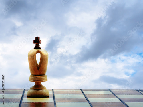 Wooden White King Chess Piece On A Chess Board Against A Cloudy Sky
