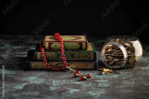Zakat concept: Quran and tasbih with jar full of coins photo