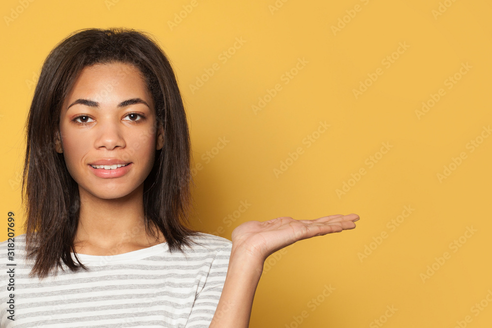 Pretty woman holding empty open hand on yellow background Pretty woman holding empty open hand on yellow background