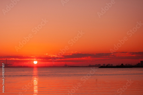 Sunset in a bay near the city. Bright warm red colores. A silhouette of city centre. Asymmetrical composition