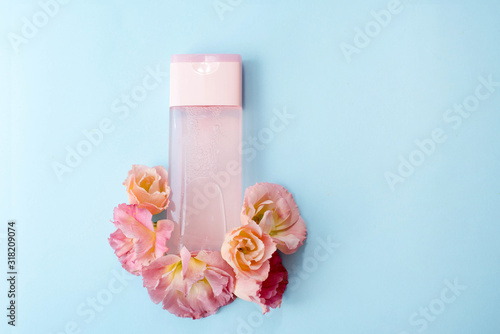 Pink bottle women's perfume with spring flowers on blue background with a copy space